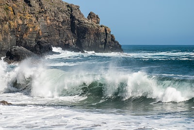 Wave impact brown rocks during the day
